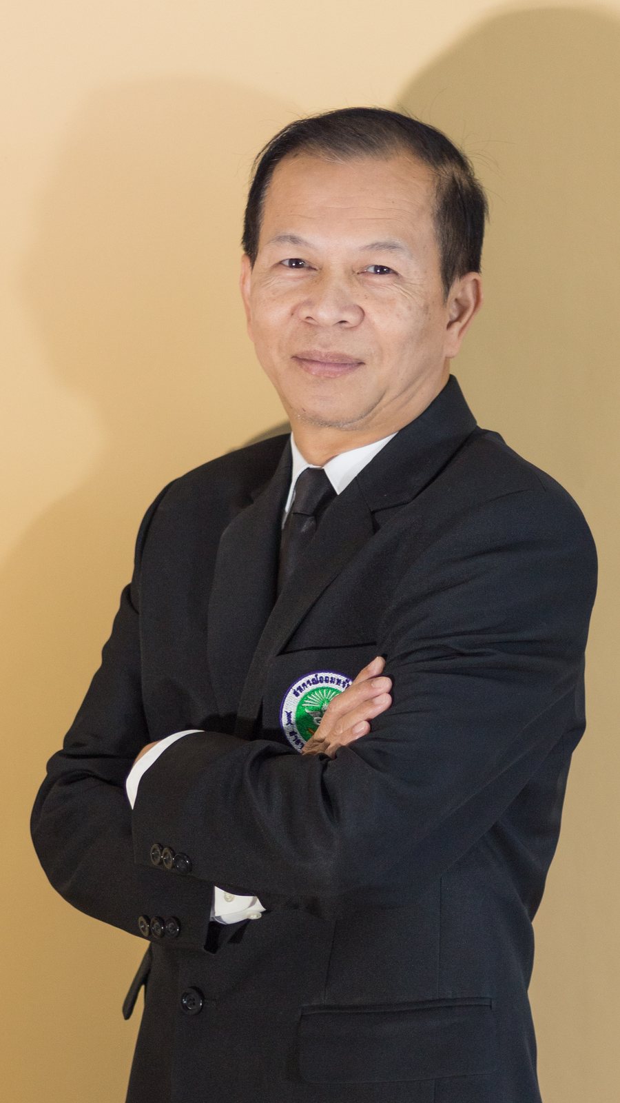 นายวุฒิพงศ์ ชื่นมณี กอดอกยิ้มอย่างมั่นใจ ในชุดสูท