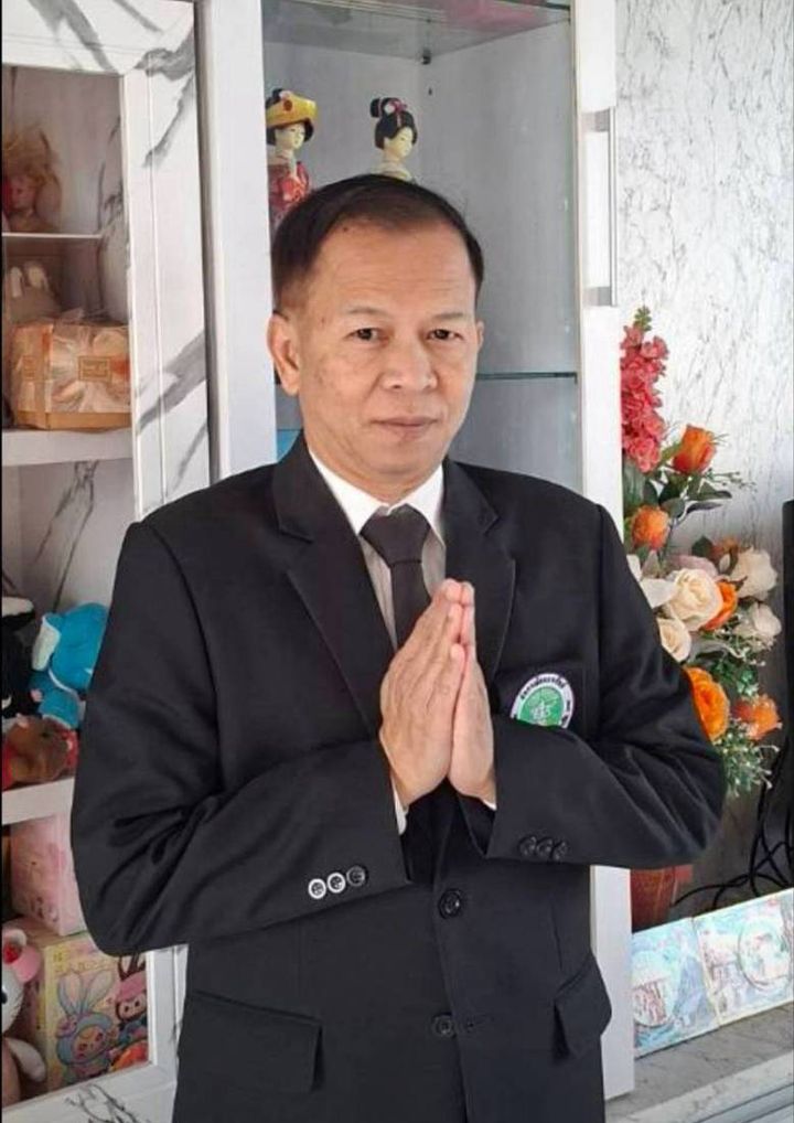 นายวุฒิพงศ์ ในชุดสูทไหว้สวัสดี