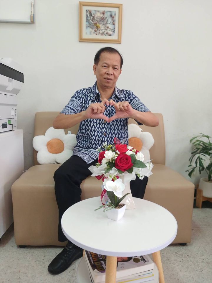 นายวุฒิพงศ์ นั่งบนโซฟาทำมือรูปหัวใจ