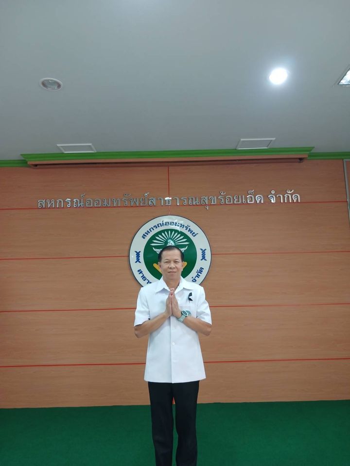นายวุฒิพงศ์ ยืนหน้าป้ายสหกรณ์ออมทรัพย์สาธารณสุขจังหวัดร้อยเอ็ด